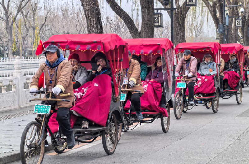 2024年12月12日，外国游客在北京什刹海乘坐人力三轮车观光。新华社记者 鞠焕宗 摄